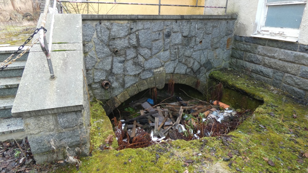 vermüllter Auslauf des überbauten Mühlgrabens unter der Terrasse, vor der Radgrube