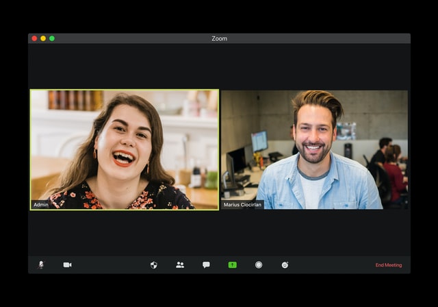 Eine Frau und ein Mann lachen während eines Online-Meetings.