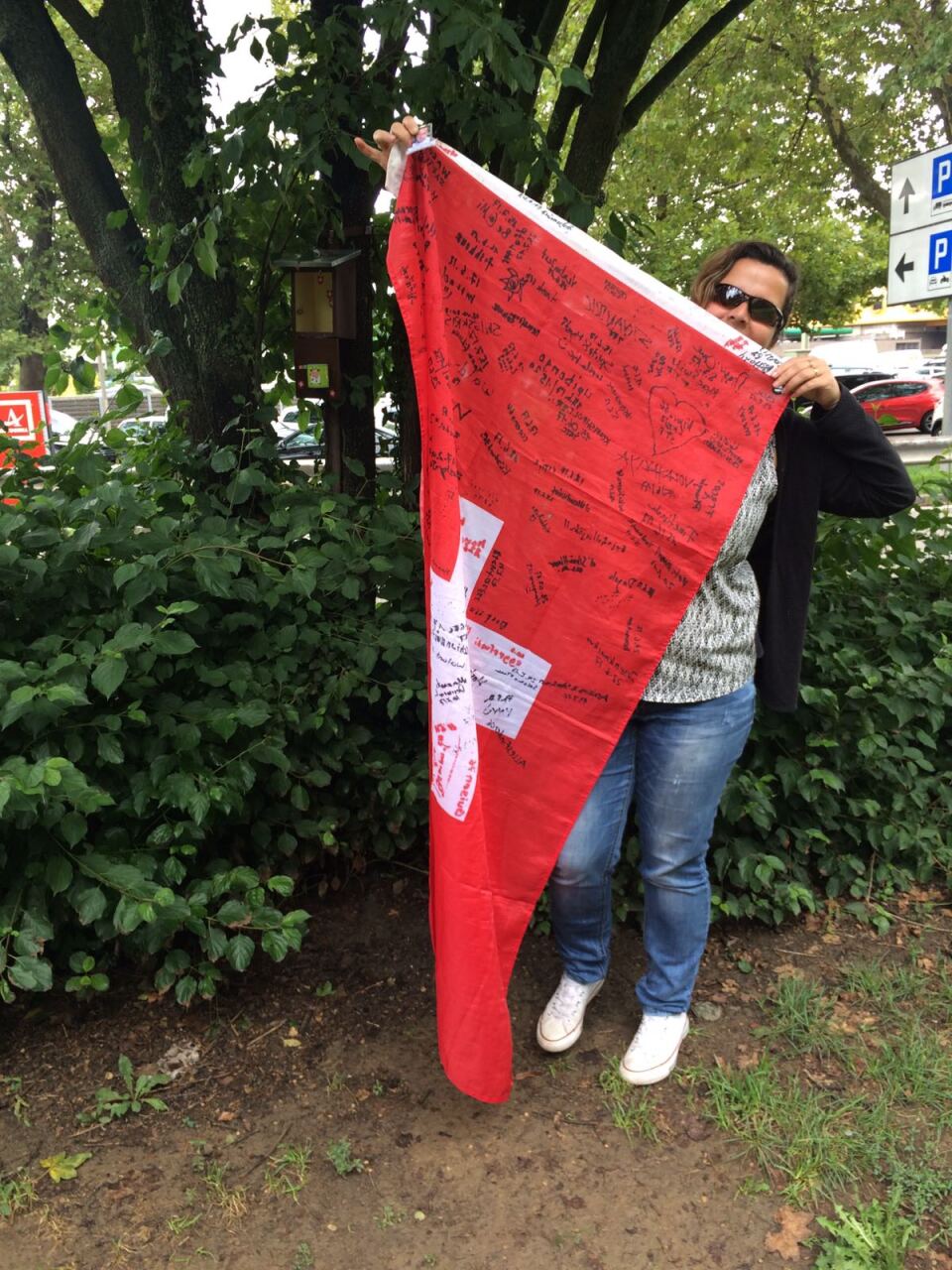 Geocachelocatie in Zwitserland met een grote Zwitserse vlag waar geocachers uit verschillende landen hun handtekening achterlaten.