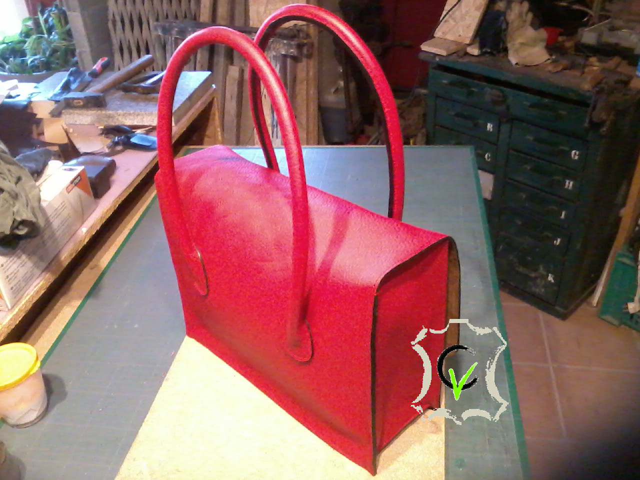 Sac a mains en cuir rouge grainé, deux poignées pleine cousues mains, doublure en mouton velours beige et cuir tannage végétal naturel, une séparation en mouton noir, une poche, 3 pochettes et une poche pour stylo. Finition sellier