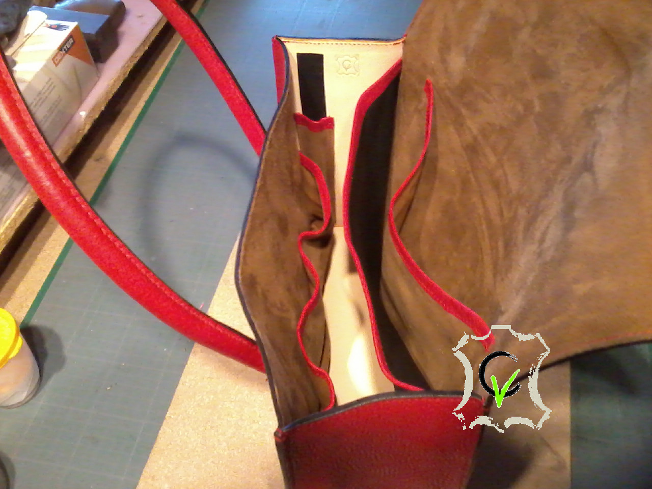 Sac a mains en cuir rouge grainé, deux poignées pleine cousues mains, doublure en mouton velours beige et cuir tannage végétal naturel, une séparation en mouton noir, une poche, 3 pochettes et une poche pour stylo. Finition sellier