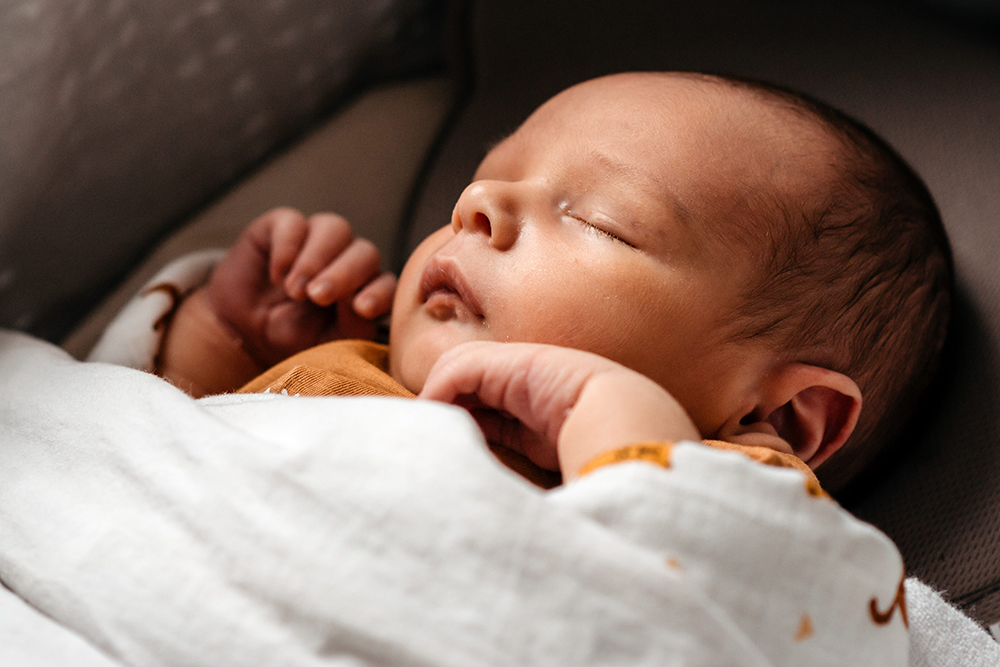 close-up van het gezichtje van een slapende baby in zijn wiegje-newbornfotografie-byFotografils-IlseWagemakers-fotograaf gevestigd in Essen, Antwerpen, België