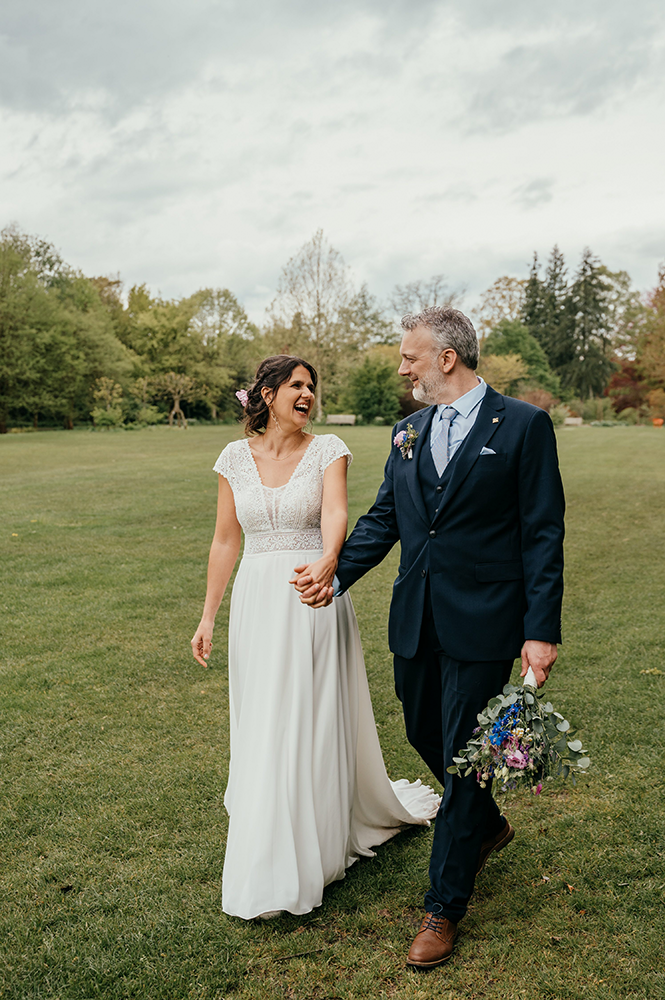 bruid en bruidegom wandelen al lachend door het Arboretum-huwelijksfotografie-trouwreportage-byFotografils-IlseWagemakers-Fotograaf gevestigd in Essen