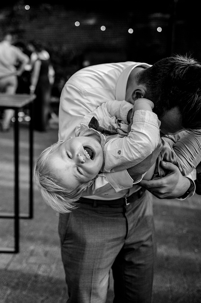 bruidsjonker lacht in de camera terwijl hij geknuffeld wordt-huwelijksfotografie-trouwreportage-byFotografils-IlseWagemakers-Fotograaf gevestigd in Essen