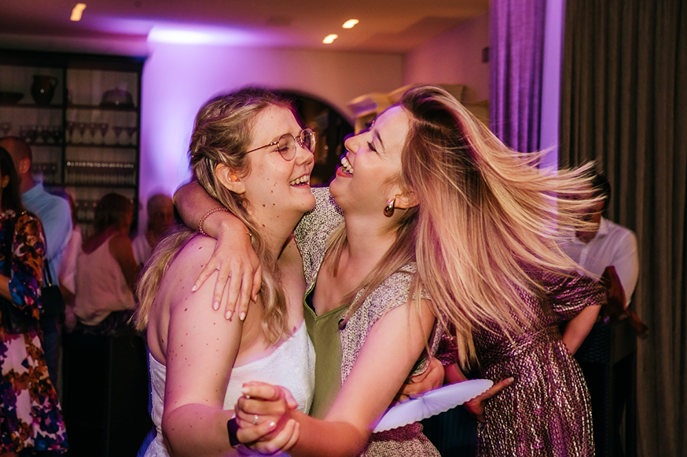 bruid danst met vriendin tijdens haar huwelijksfeest-huwelijksfotografie-trouwreportage-byFotografils-IlseWagemakers-Fotograaf gevestigd in Essen