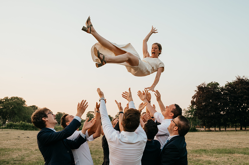 mannen gooien de bruid hoog op in de lucht; ze gilt zichtbaar-huwelijksfotografie-trouwreportage-byFotografils-IlseWagemakers-Fotograaf gevestigd in Essen