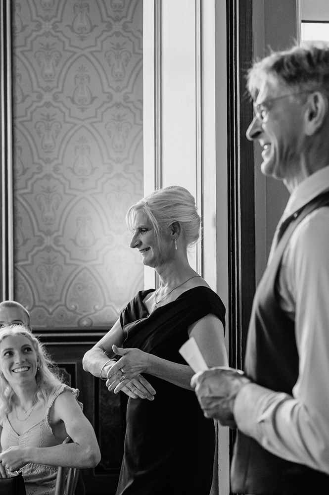 dame maakt al lachend een 'zaaggebaar' terwijl haar man een speech houdt-huwelijksfotografie-trouwreportage-byFotografils-IlseWagemakers-Fotograaf gevestigd in Essen