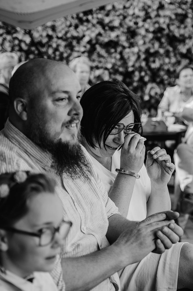 gasten op een huwelijk zijn geëmotioneerd; de man applaudisseert, de dame pinkt een traan weg-huwelijksfotografie-trouwreportage-byFotografils-IlseWagemakers-Fotograaf gevestigd in Essen