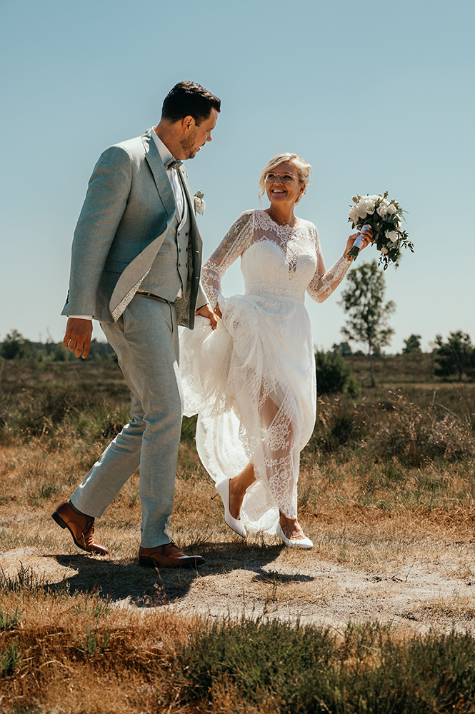 wandelend bruispaar door de heide-huwelijksfotografie-trouwreportage-byFotografils-IlseWagemakers-Fotograaf gevestigd in Essen