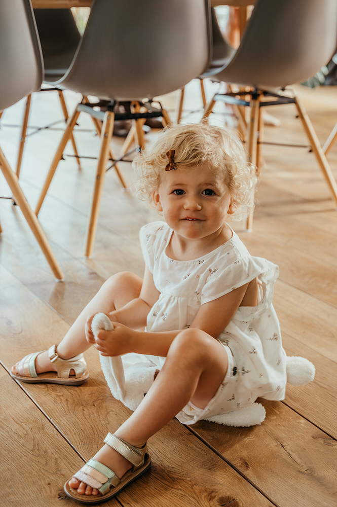 bruidsmeisje kijkt guitig in de camera, zittend op de grond-huwelijksfotografie-trouwreportage-byFotografils-IlseWagemakers-Fotograaf gevestigd in Essen