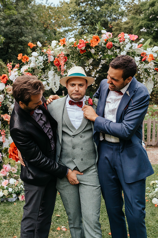 twee vrienden leggen de kleding van de bruidegom goed; één van de vrienden knijpt in zijn kruis waarop de bruidegom een gek gezicht trekt-huwelijksfotografie-trouwreportage-byFotografils-IlseWagemakers-Fotograaf gevestigd in Essen