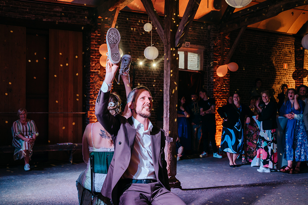 bruidegom en bruid spelen een spel met het in de lucht steken van hun schoenen-huwelijksfotografie-trouwreportage-byFotografils-IlseWagemakers-Fotograaf gevestigd in Essen