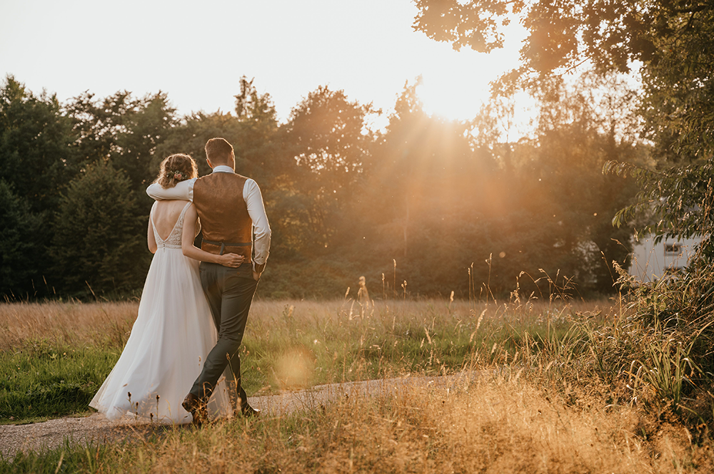 bruidspaar wandelt de zonsondergang tegemoet tijdens golden hour-huwelijksfotografie-trouwreportage-byFotografils-IlseWagemakers-Fotograaf gevestigd in Essen