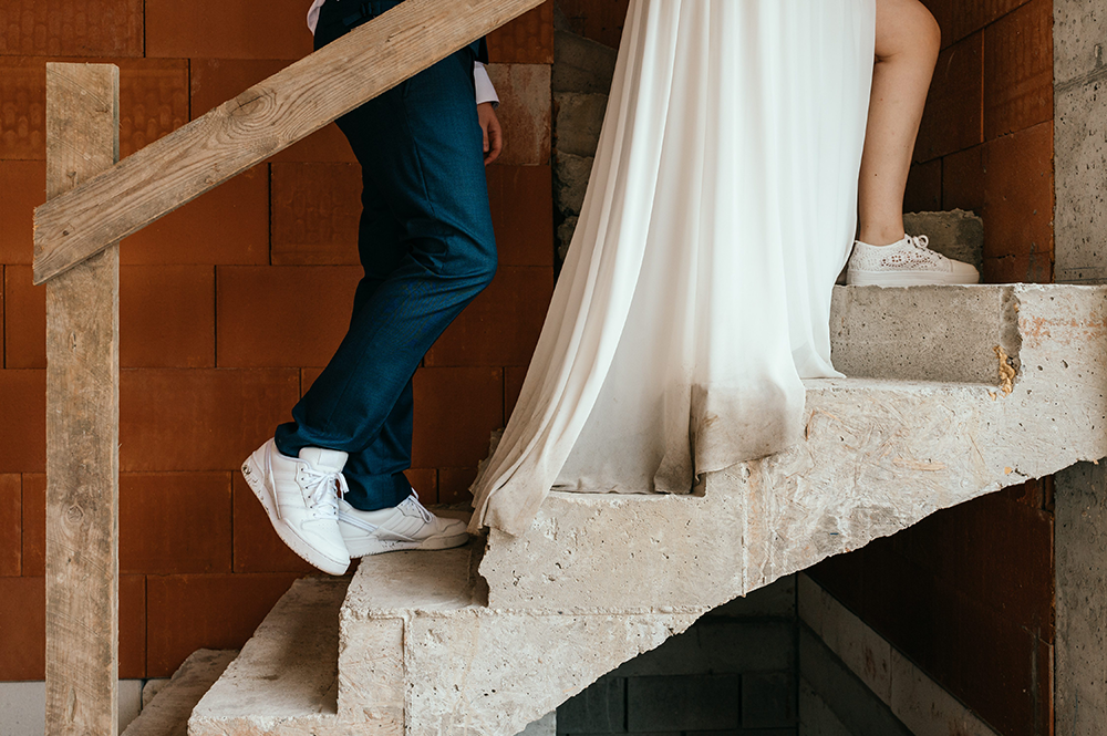 close-up van de benen en schoenen van het bruidspaar die in hun huis in aanbouw, op de toekomstige trap, werd gefotografeerd-huwelijksfotografie-trouwreportage-byFotografils-IlseWagemakers-Fotograaf gevestigd in Essen