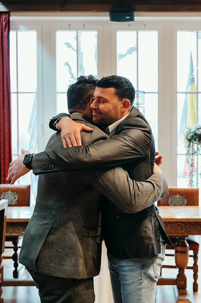 omhelzing van de getuige en de bruidegom na de plechtigheid-huwelijksfotografie-trouwreportage-byFotografils-IlseWagemakers-Fotograaf gevestigd in Essen