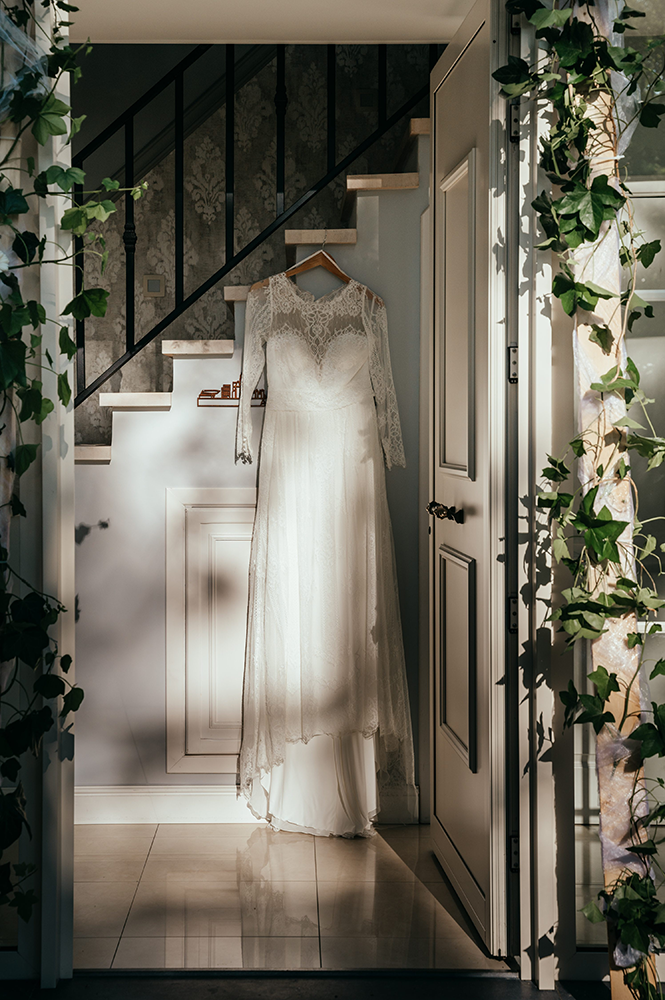 sfeerfoto van bruidsjurk op kledinghanger in spel van schaduw en licht-huwelijksfotografie-trouwreportage-byFotografils-IlseWagemakers-Fotograaf gevestigd in Essen