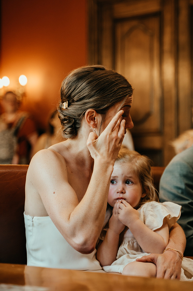 bruid pinkt een traantje weg en houdt terwijl een droevig kijkende kleuter op de schoot-huwelijksfotografie-trouwreportage-byFotografils-IlseWagemakers-Fotograaf gevestigd in Essen