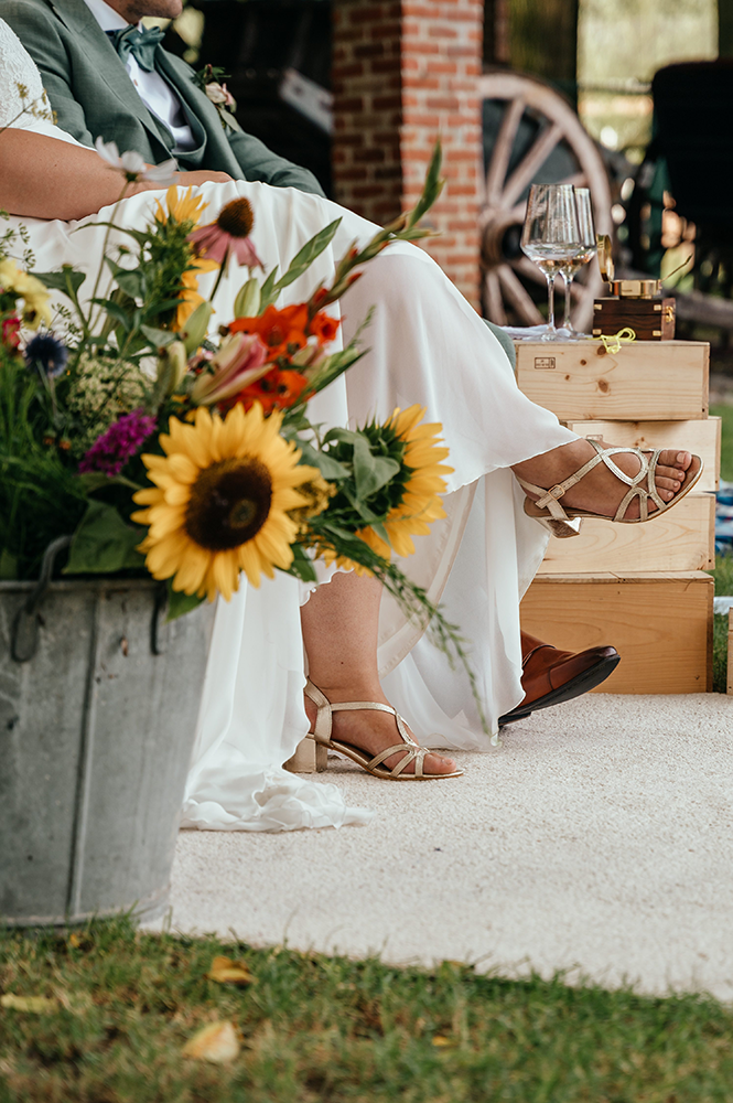 foto van de schoenen van de bruid, langsheen de bloemendecoratie van de ceremonie gefotografeerd-huwelijksfotografie-trouwreportage-byFotografils-IlseWagemakers-Fotograaf gevestigd in Essen