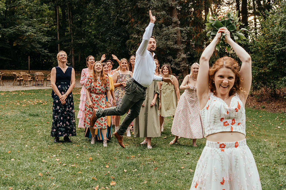 de bruid wil het boeket gooien en op dat moment komt er een man voor de dames gesprongen om het boeket zogezegd te onderscheppen-huwelijksfotografie-trouwreportage-byFotografils-IlseWagemakers-Fotograaf gevestigd in Essen