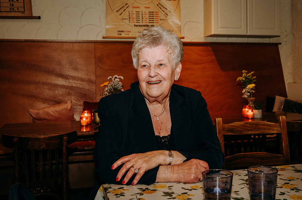 oudere dame zit lachend toe te kijken-huwelijksfotografie-trouwreportage-byFotografils-IlseWagemakers-Fotograaf gevestigd in Essen