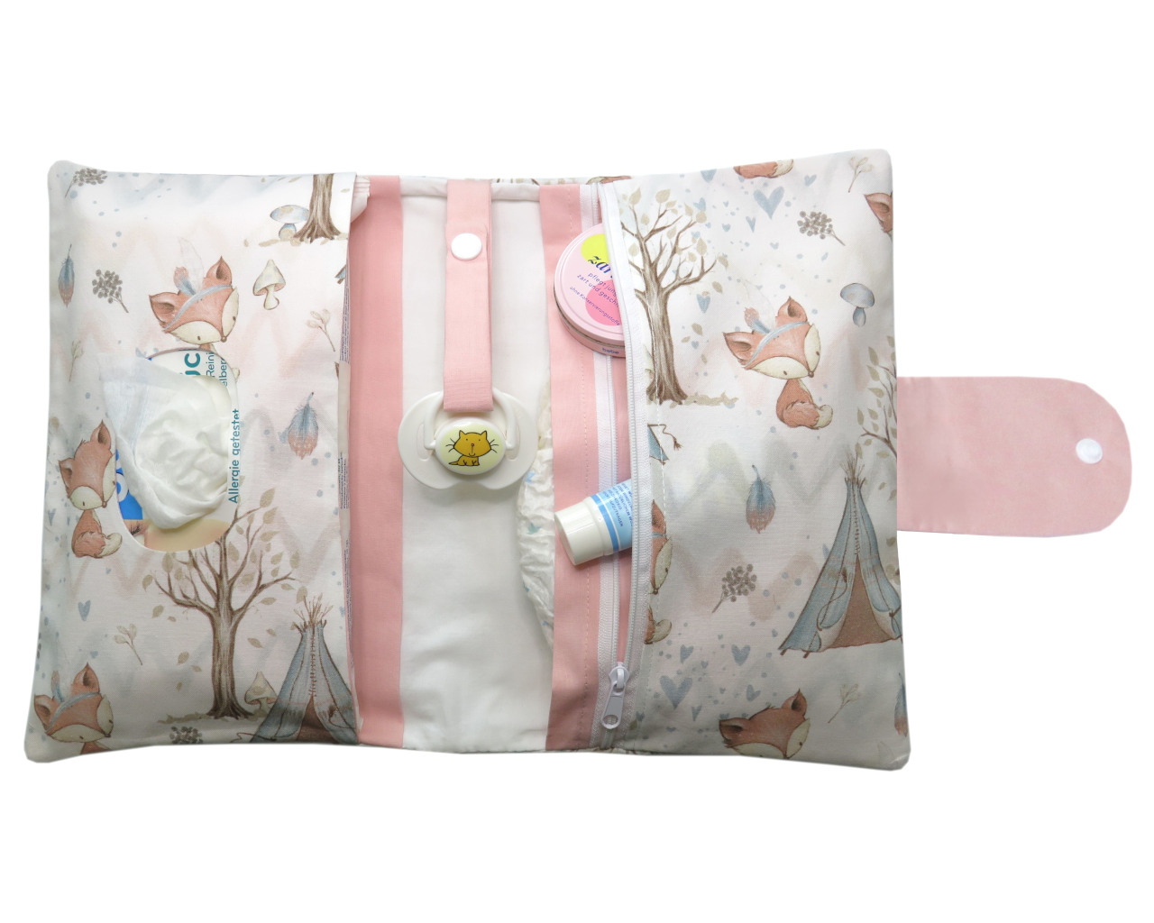 Windeltasche/ wickeltasche aus Stoff mit niedlichen fuchs, Bäumen und einer rosa Verschlusslasche mit Druckknopf. Die windeltasche ist geöffnet und zeigt eine Reißverschlusstasche, Feuchttücherfach und mittig ein Schnullerband mit Schnuller.