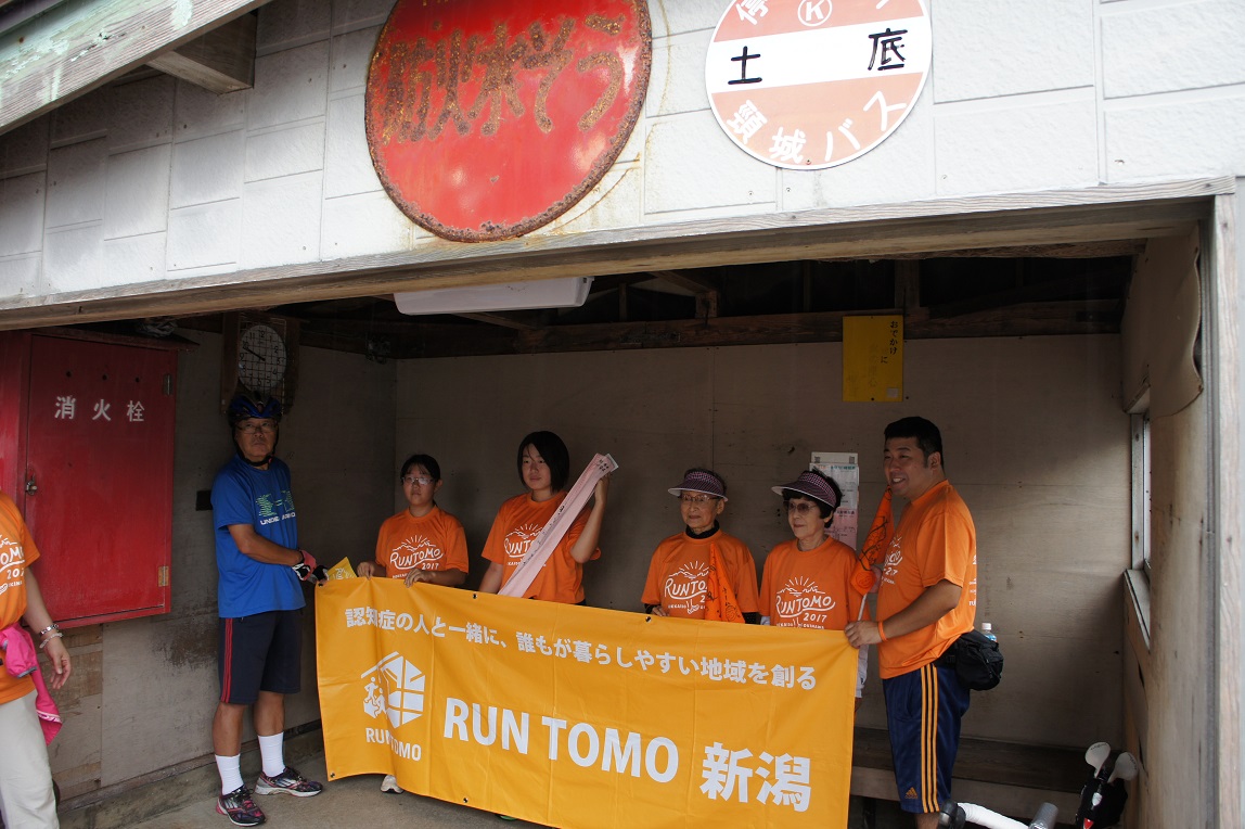 第１中継点の「土底浜公民館」前。バス停の中でタスキの引き継ぎ式