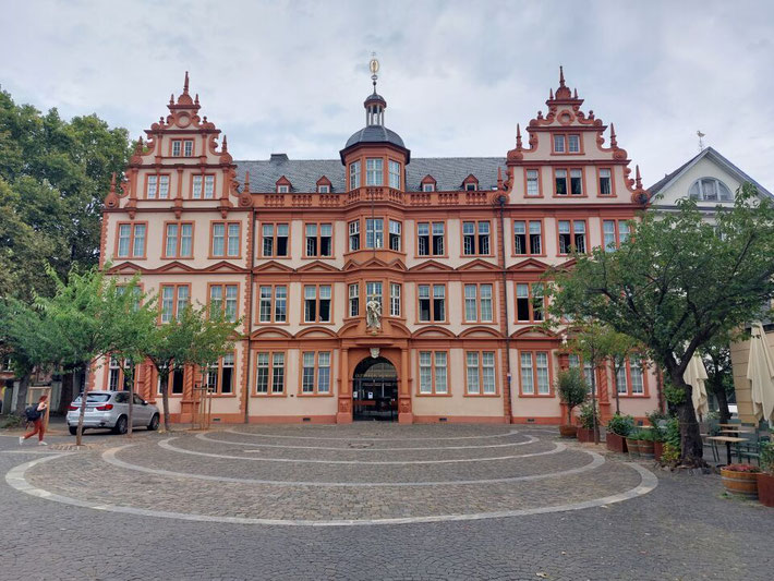 Die prunkvolle, rote Fassade des Kurfürstlichen Schlosses in Mainz unter blauem Himmel