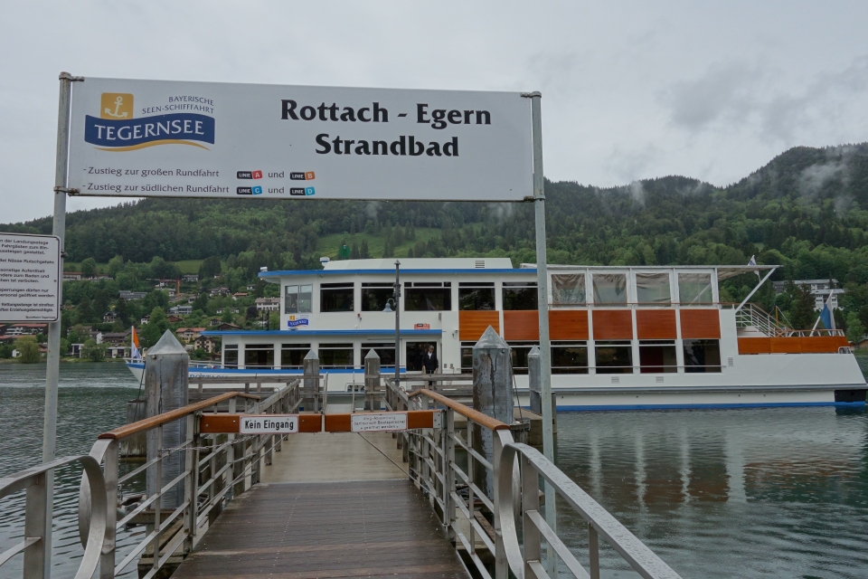 Blick auf die Schiffsanlegestelle am Tegernsee mit dem Fahrplan-Schild im Vordergrund