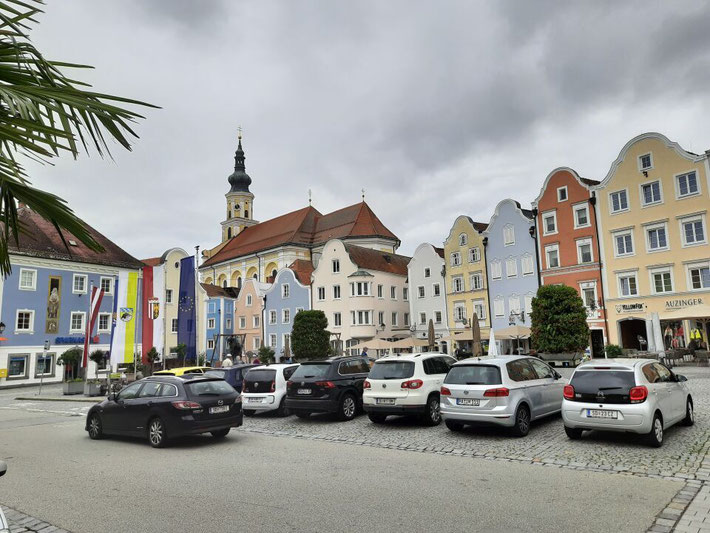 Blick über den belebten Schärdinger Stadtplatz mit historischen Gebäuden und geparkten Autos