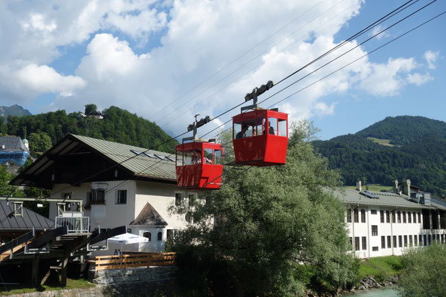 Die roten Kabinen der Obersalzbergbahn schweben vor der Bergkulisse von Berchtesgaden