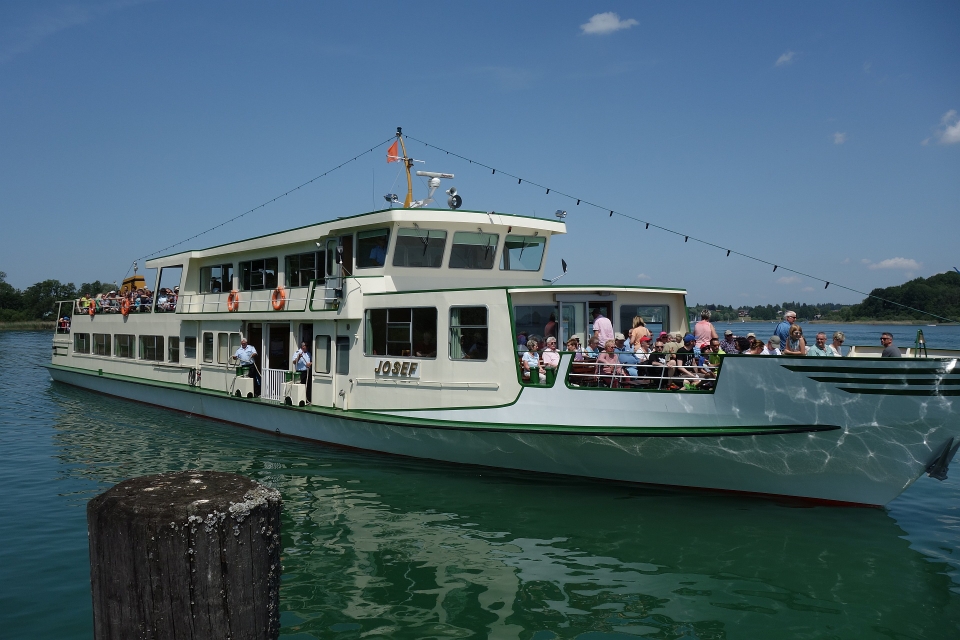 Ein großes weißes Fahrgastschiff der Chiemsee-Schifffahrt legt im Hafen von Prien-Stock an