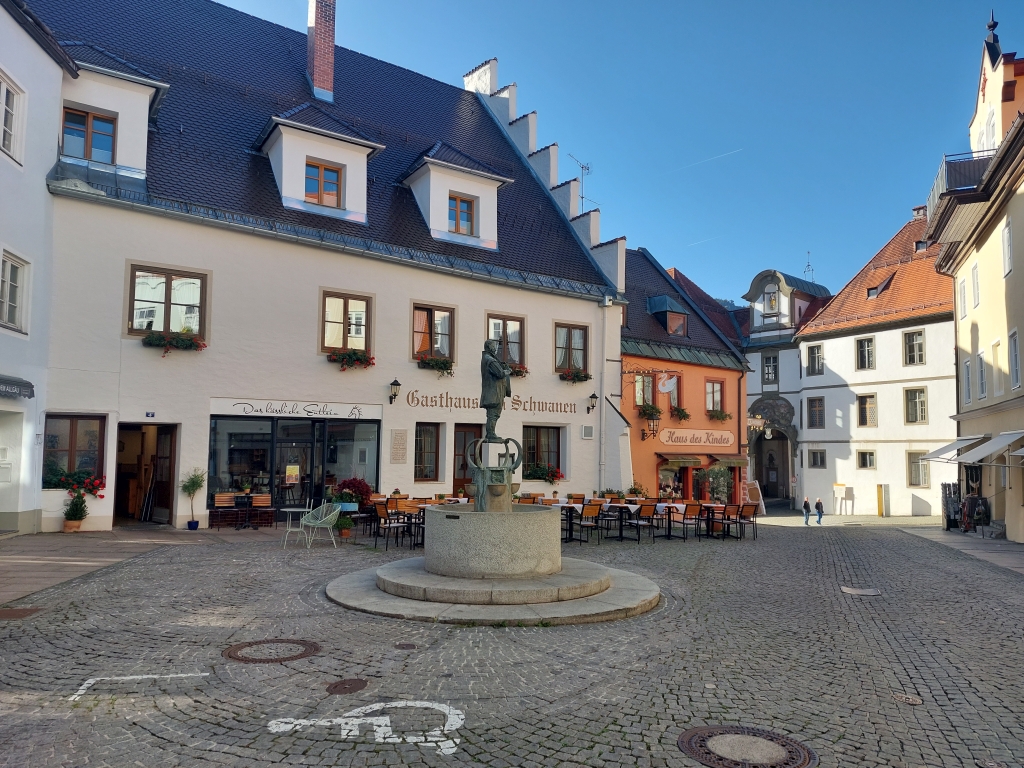 Ein weiter Platz in Füssen mit Blick auf das Hohe Schloss im Hintergrund
