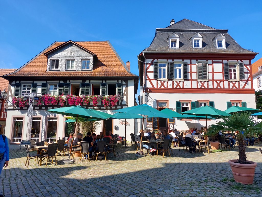 Historische Fachwerkhäuser am Marktplatz von Heppenheim mit gemütlicher Außengastronomie unter Sonnenschirmen