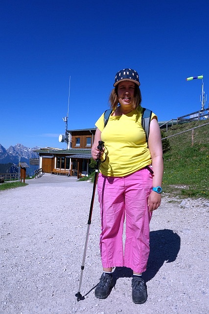Christina steht auf einem steinigen Pfad vor einer urigen Berghütte
