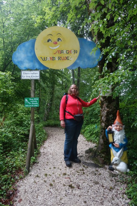 Christina am Startpunkt des Märchenwegs mit bunten Holzfiguren