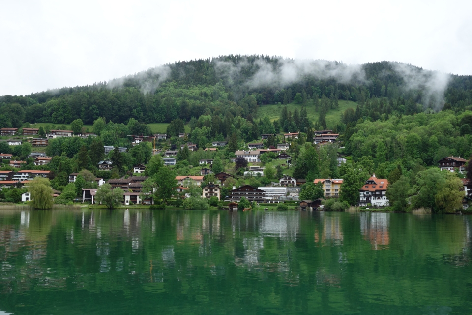 Panorama-Aussicht vom Schiff auf die bewaldeten Berge und die Orte am Ufer des Tegernsees