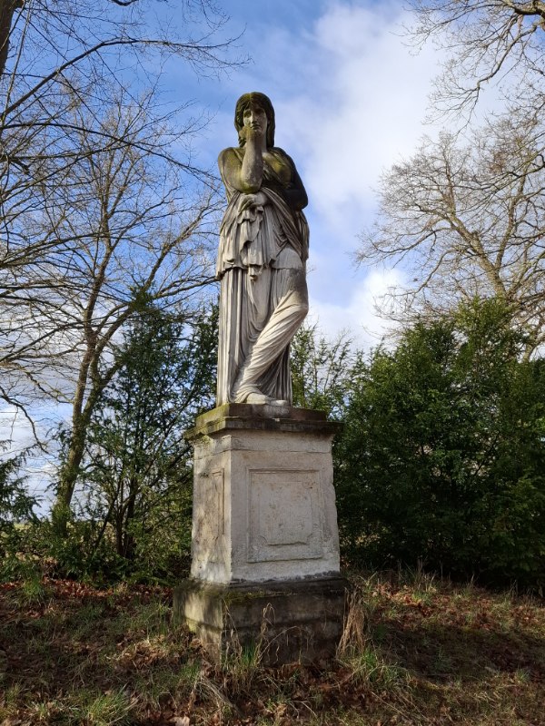 Historische Skulptur auf Sockel im Schlosspark