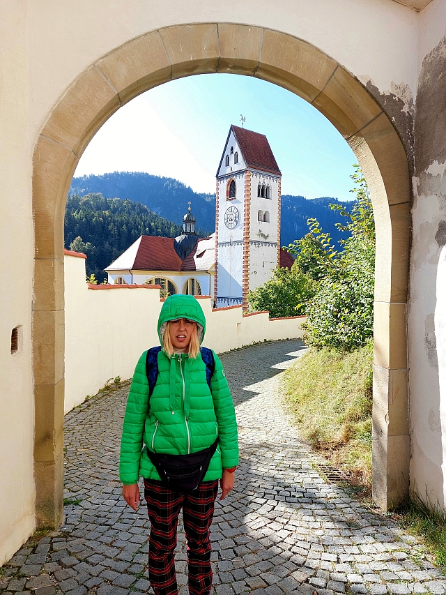 Christina steht in einem Torbogen mit Blick auf die Stadtpfarrkirche St. Nikolaus