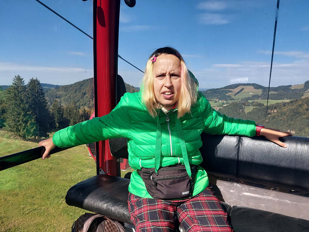 Christina im grünen Wander-Outfit steht freudestrahlend auf einem Bergpfad am Hündle