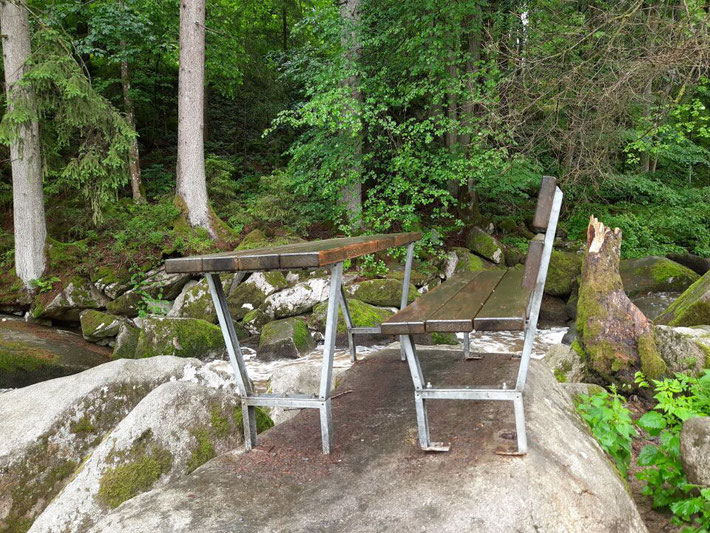 Zwei hölzerne Sonnenstühle stehen für eine Pause am Ufer des Saußbachs bereit