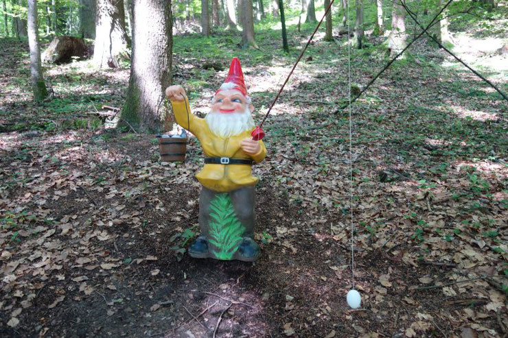 Eine bunt bemalt Märchenfigur eines Zwerges am Wegrand im Kindermärchenwald am Attersee