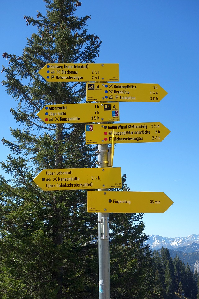 Gelber Wegweiser am Berg zeigt Richtungen zu verschiedenen Wanderzielen