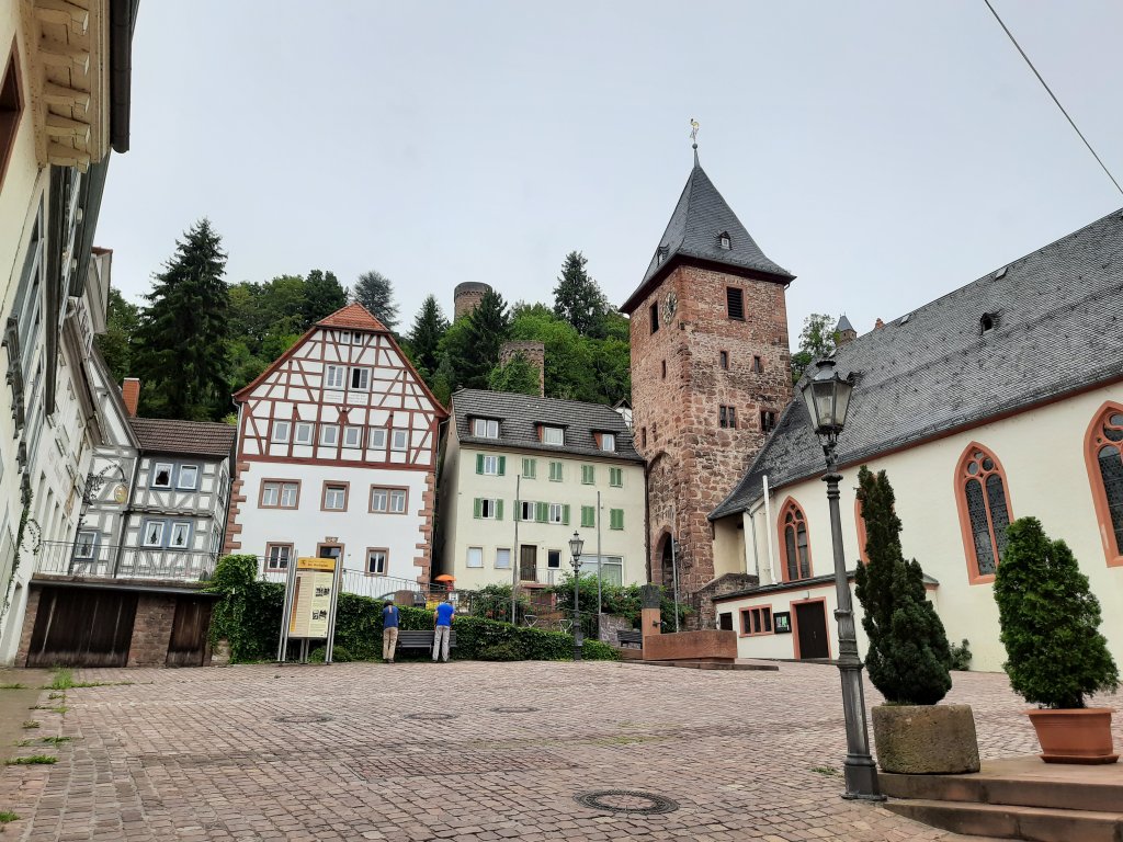 Blick über einen gepflasterten Platz in Hirschhorn mit Fachwerkhäusern und dem Mitteltor im Hintergrund