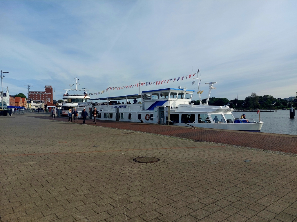 Blick über die Hafenpromenade von Kappeln mit mehreren Schiffen und der Schlei im Hintergrund