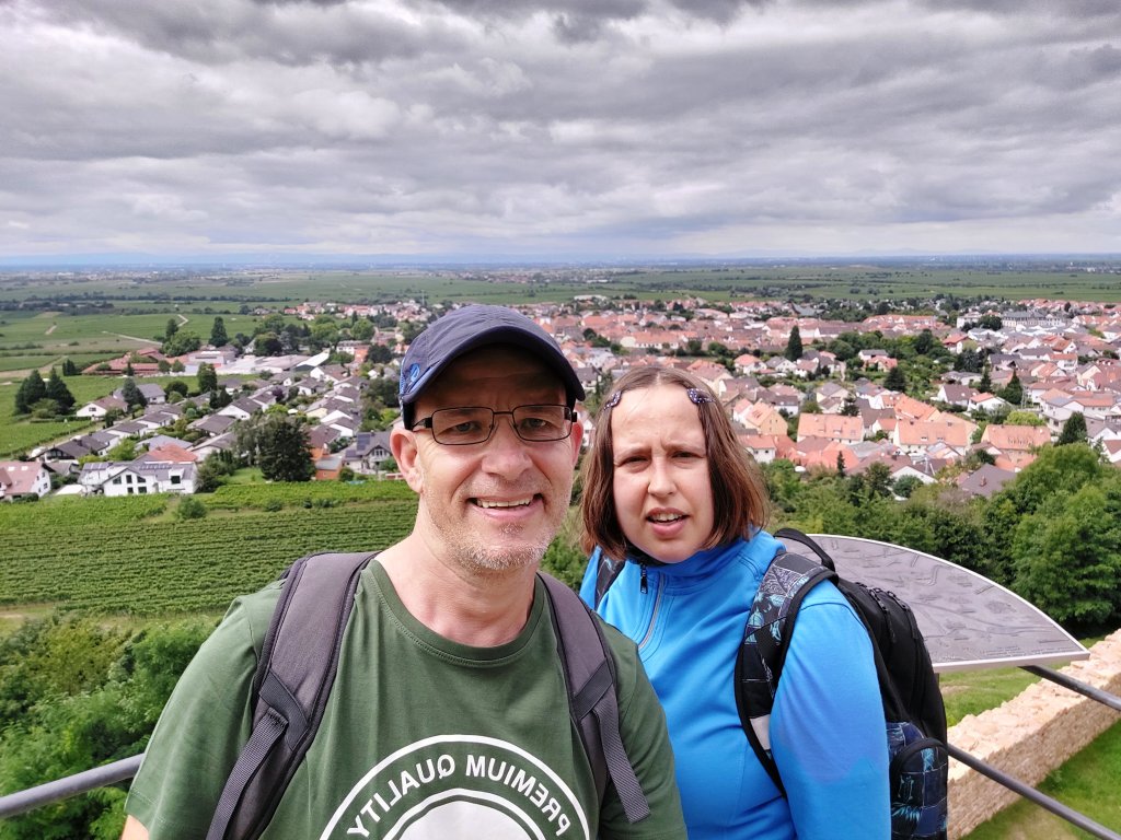 Ein glückliches Paar steht auf der Aussichtsplattform der Ruine Wachtenburg vor der weiten Landschaft der Pfalz