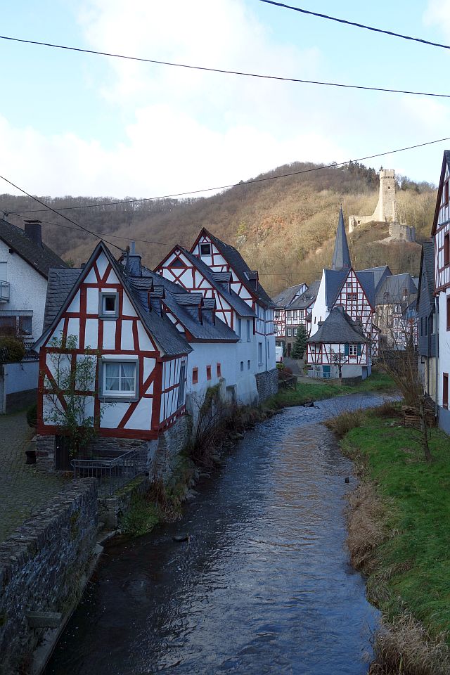 Malerischer Blick auf die Fachwerkhäuser von Monreal, die direkt am Ufer des kleinen Flusses Elz stehen