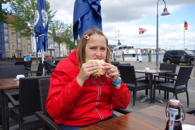 Eine Frau in roter Jacke beim Essen im Restaurant "Hafen Liebe
