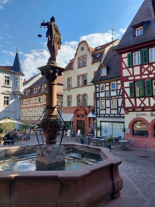 Der historische Marktbrunnen vor der Kulisse bunter Fachwerkhäuser am Weinheimer Marktplatz