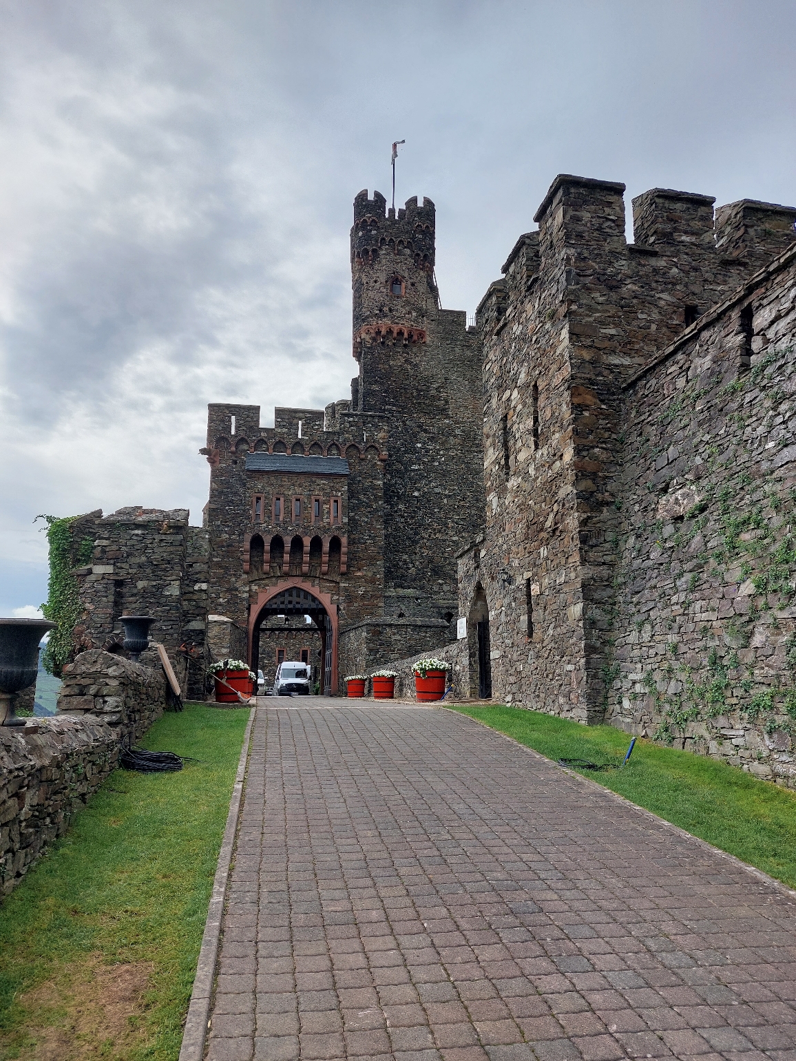 Die markante neugotische Architektur der Burg Reichenstein mit ihren Zinnen und Türmen vor bewölktem Himmel