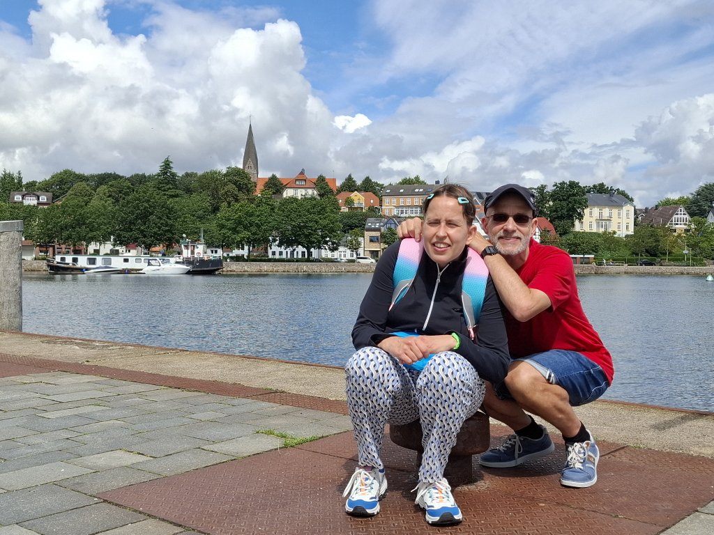 Andreas und Christina sitzen lächelnd auf einer Bank am Wasser in Eckernförde